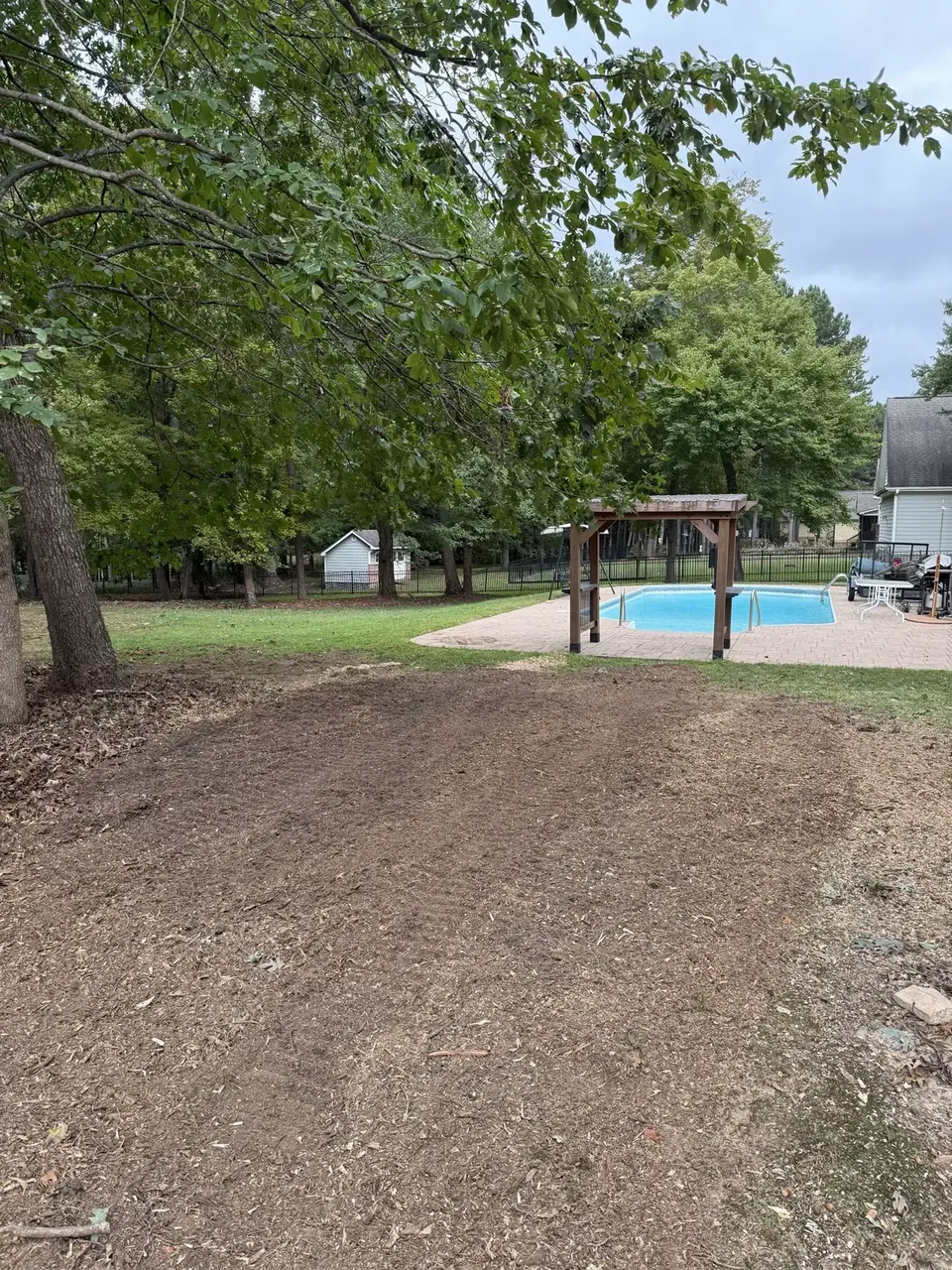Fonvilletreeservice freshly cleared and graded yard area near backyard pool with mature trees in residential NC property