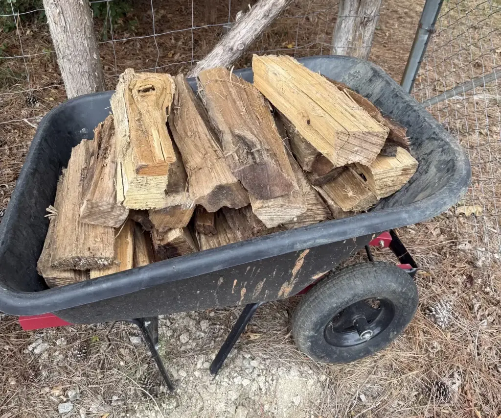 Fonvilletreeservice split seasoned hardwood firewood stacked in black wheelbarrow ready for delivery in rural NC setting