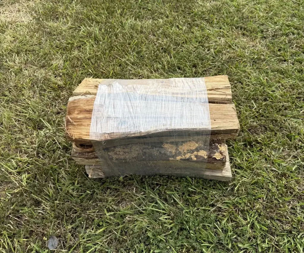 Fonvilletreeservice bundled seasoned hardwood firewood logs wrapped in plastic sitting on green grass lawn in NC