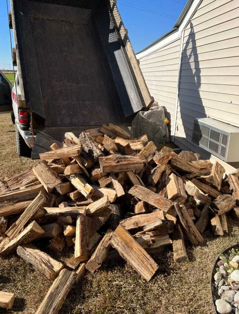 Fonvilletreeservice dump truck unloading large pile of split seasoned hardwood firewood at residential property in NC