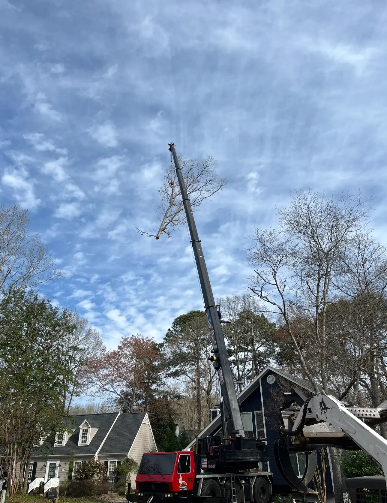 Fonvilletreeservice crane operator lifting large tree section above residential neighborhood during professional tree removal in NC