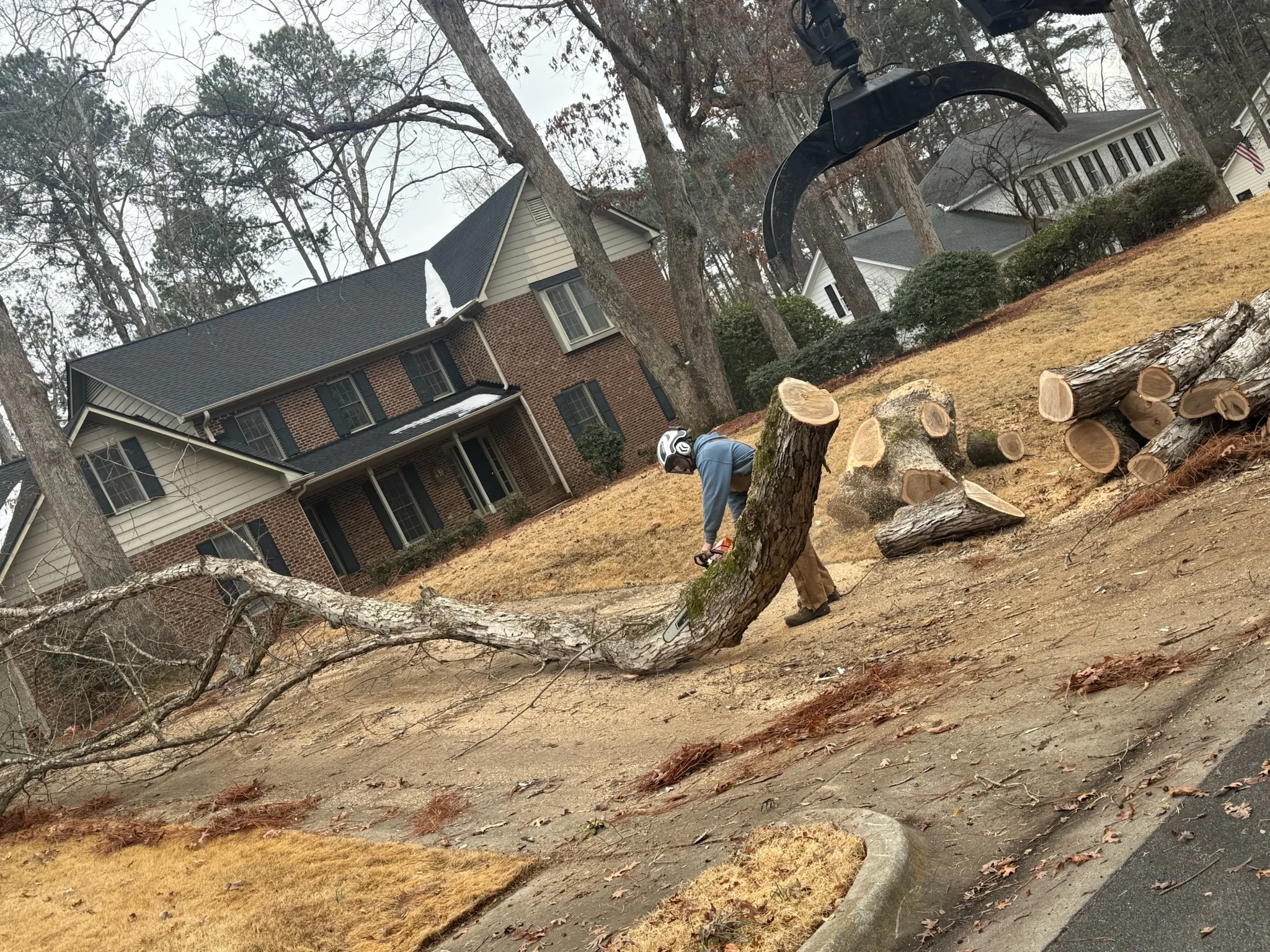 Fonvilletreeservice crew member using chainsaw to cut fallen tree trunk on residential hillside property in NC