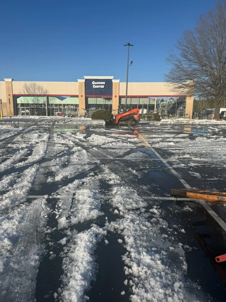 Fonvilletreeservice crew operates orange Kubota skid steer clearing snow and ice from commercial parking lot in NC.