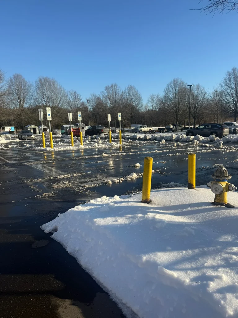 Fonvilletreeservice winter parking lot scene with snow piles yellow bollards and fire hydrant after clearing in NC