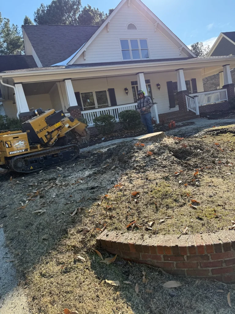 Fonvilletreeservice crew member operating yellow Rayco stump grinder to remove tree stump in residential front yard in NC